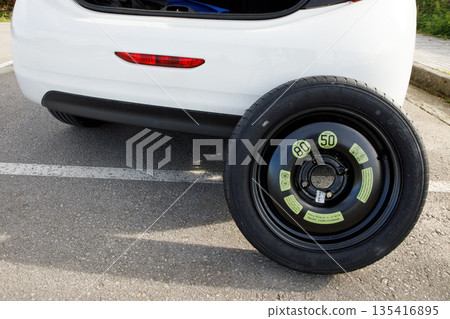 a temporary spare wheel resting on the car, ready to be changed 135416895