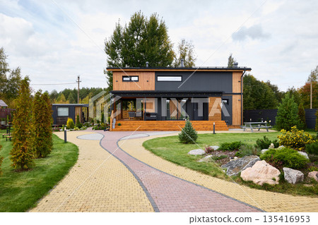 Modern wooden facade house featuring landscaped gardens and privacy fencing 135416953