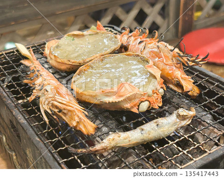Crab shell grilled with miso, seafood being grilled on a grill 135417443