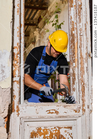Worker carefully examining window frame with protective gear on Worker carefully examining window frame with protective gear on 135418187