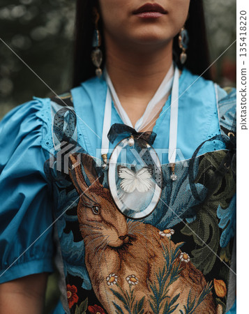 Softly lit portrait showcasing ornate necklace and textured fabric details 135418220