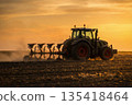 Tractor plowing field at sunset. Agricultural machinery working in soil. 135418464