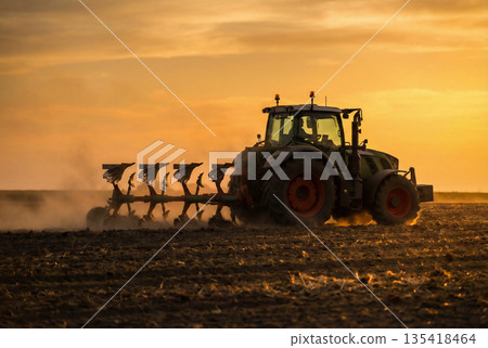 Tractor plowing field at sunset. Agricultural machinery working in soil. Tractor plowing field at sunset. Agricultural machinery working in soil. 135418464