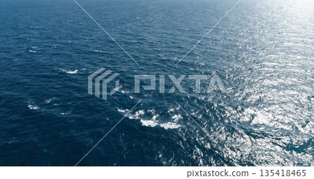 Blue ocean water surface texture. Aerial view of sea waves and sun reflection background. 135418465