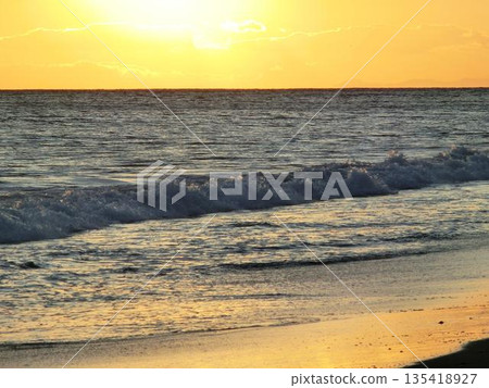 夕陽西下，海浪拍打著沙灘 135418927
