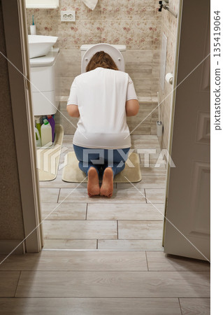 Woman kneeling in bathroom, experiencing morning sickness or illness Woman kneeling in bathroom, experiencing morning sickness or illness 135419064