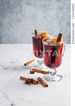Two glasses of mulled wine, orange, cinnamon, and star anise on a marble background with spice. 135419081