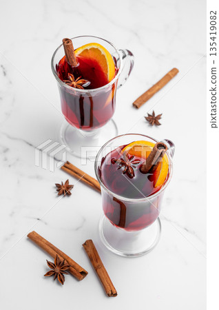 Two glasses of mulled wine, orange, cinnamon, and star anise on a marble background with spice. 135419082