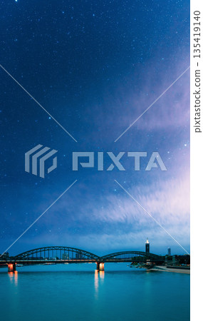 Night View Of Hohenzollern Arch Bridge Over The River Rhine, Germany. Europe. Cologne. Night starry sky with stars in blue heaven 135419140