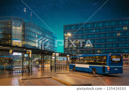 Helsinki, Finland. Bus Is At Stop On Helsinki Railway Square. Square Serves As Helsinki Secondary Bus Station And Main Kamppi Center Bus Station. Night stars shining above street Helsinki, Finland. Bus Is At Stop On Helsinki Railway Square. Square Serves As Helsinki Secondary Bus Station And Main Kamppi Center Bus Station. Night stars shining above street 135419193