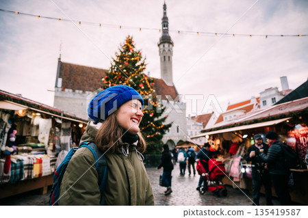 Tallinn, Estonia. Young Beautiful Pretty Caucasian Girl Woman Dressed In Green Jacket And Blue Hat Enjoying Life And Smiling On Background Christmas Xmas New Year Market 135419587