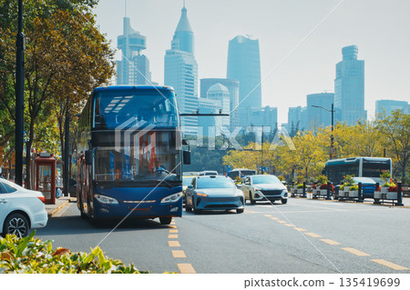 Public bus in motion against a backdrop of tall skyscrapers and blue skies. Shanghai, China Public bus in motion against a backdrop of tall skyscrapers and blue skies. Shanghai, China 135419699