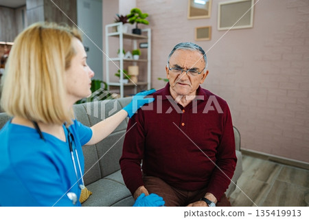 Caring nurse interacts with elderly man in cozy home Caring nurse interacts with elderly man in cozy home 135419913
