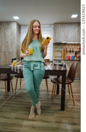 Happy morning in a bright kitchen with fresh juice and technology Happy morning in a bright kitchen with fresh juice and technology 135419923