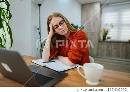 Focused student reviews study materials at cozy home workspace Focused student reviews study materials at cozy home workspace 135419932