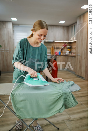 Joyful moments of ironing a shirt in a cozy kitchen space 135419936