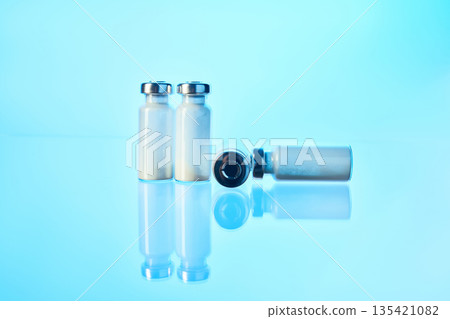 Medical vials containing vaccine powder on blue surface 135421082