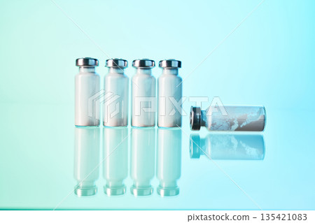 Medical vials containing powder reflecting on blue surface Medical vials containing powder reflecting on blue surface 135421083