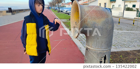 A child throws trash into a pipe-shaped trash can. Concepts of environmental responsibility, waste recycling, reuse, and teaching sustainable development principles A child throws trash into a pipe-shaped trash can. Concepts of environmental responsibility, waste recycling, reuse, and teaching sustainable development principles 135422002