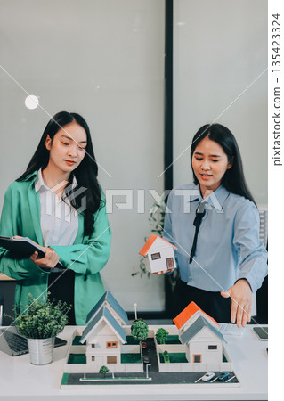 Professional real estate agents brainstorming house project while planning home investment with architectural model and documents Professional real estate agents brainstorming house project while planning home investment with architectural model and documents 135423324