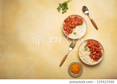 Indian chicken curry with rice and turmeric on yellow background with copy space top view Indian chicken curry with rice and turmeric on yellow background with copy space top view 135423588