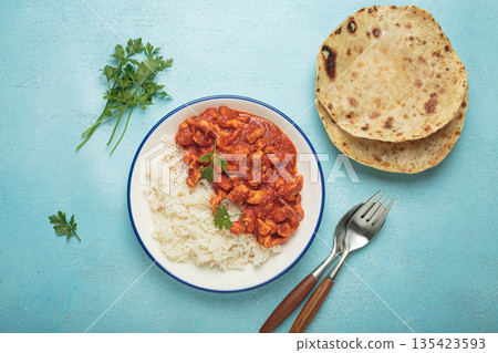 Indian chicken curry with basmati rice served on plate with chapati flatbread on the side top view Indian chicken curry with basmati rice served on plate with chapati flatbread on the side top view 135423593