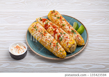 Delicious Mexican dish Elotes corn cob covered in spices and cheese 135423594