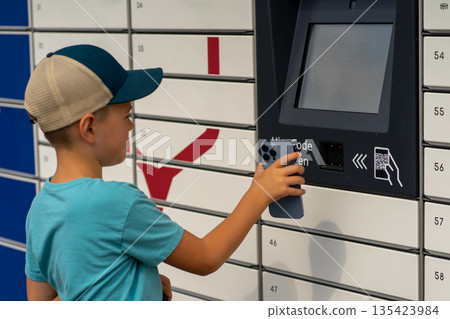 A boy receives a parcel in one of the parcel lockers. 135423984