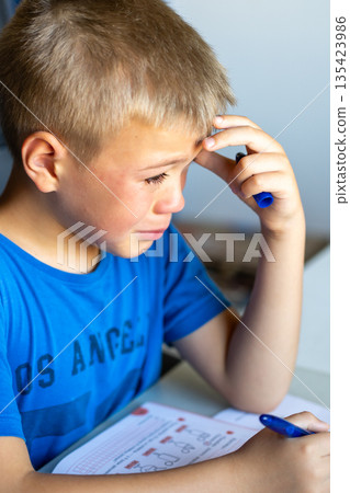 A boy in a blue T-shirt is crying over school. A boy in a blue T-shirt is crying over school. 135423986