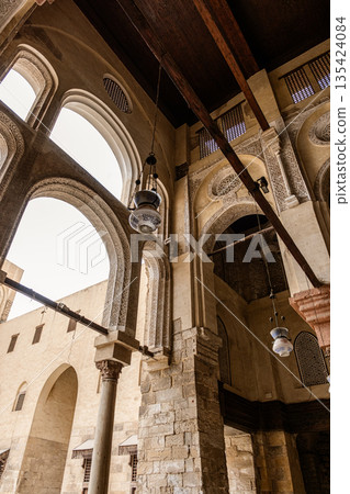 Qalawun complex interior at Al-Muizz Street. Features Islamic architecture with arches, intricate designs, and a central courtyard with greenery. Qalawun complex interior at Al-Muizz Street. Features Islamic architecture with arches, intricate designs, and a central courtyard with greenery. 135424084