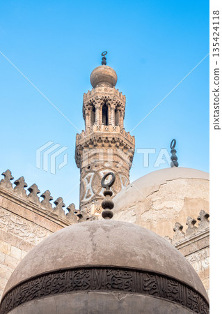 Interior view of Madrasa Al-Kamil Ayyub on Al-Muizz Street in Cairo. Features domes and a minaret against a clear blue sky. Interior view of Madrasa Al-Kamil Ayyub on Al-Muizz Street in Cairo. Features domes and a minaret against a clear blue sky. 135424118