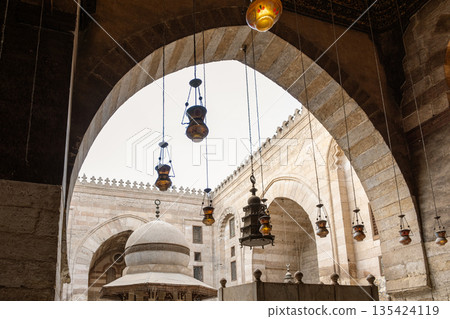 Interior view of Madrasa Al-Kamil Ayyub on Al-Muizz Street in Cairo. Features arches, decorative lanterns, and a central structure with intricate designs 135424119