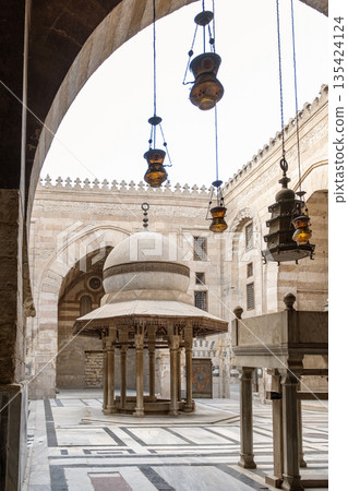 Interior view of Madrasa Al-Kamil Ayyub on Al-Muizz Street in Cairo. Features arches, decorative lanterns, and a central structure with intricate designs Interior view of Madrasa Al-Kamil Ayyub on Al-Muizz Street in Cairo. Features arches, decorative lanterns, and a central structure with intricate designs 135424124