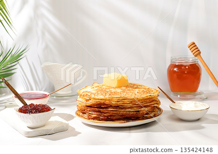 Delicious Russian pancakes with jam, soft cottage cheese, preserves, and honey on a marble table. Healthy breakfast made from natural ingredients, Maslenitsa concept, natural products 135424148