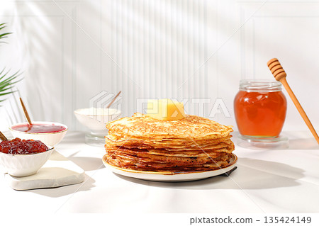 Maslenitsa concept. Delicious Russian pancakes with jam, soft cottage cheese, preserves, sour cream, and honey on a marble table. Healthy breakfast from natural ingredients, natural products 135424149