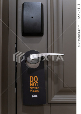 Hotel room door handle with a do not disturb sign hanging on a modern interior door, neutral tones and minimalist design Hotel room door handle with a do not disturb sign hanging on a modern interior door, neutral tones and minimalist design 135424191