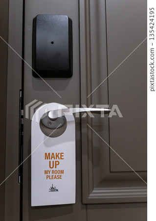 Hotel room door handle with a make up my room sign hanging on a modern interior door, neutral colors and minimal design Hotel room door handle with a make up my room sign hanging on a modern interior door, neutral colors and minimal design 135424195