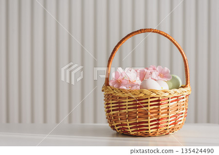 Wicker Easter Basket with Pastel Eggs and Flowers. Soft Spring Decor Wicker Easter Basket with Pastel Eggs and Flowers. Soft Spring Decor 135424490