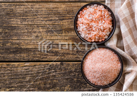 Pink Himalayan salt in bowl on wooden table. Top view. Pink Himalayan salt in bowl on wooden table. Top view. 135424586