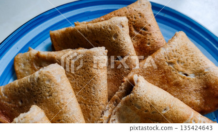 A plate of brown pastries with a blue plate underneath. Pancakes 135424643