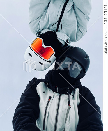 Female and male snowboarders in helmets and reflective goggles make winter selfie against clear sky. 135425161