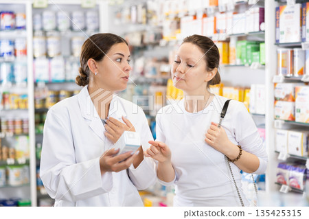 Woman pharmacist helping woman customer to choose remedy in pharmacy 135425315