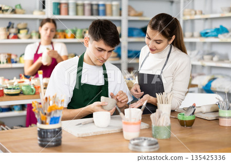 Young man and woman sculpting cups with master Young man and woman sculpting cups with master 135425336