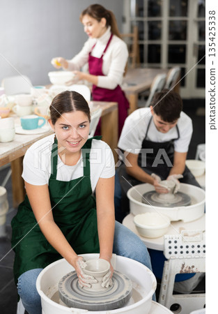 Young woman sculpting product on potter's wheel Young woman sculpting product on potter's wheel 135425338