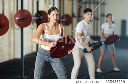 Young woman training with weight plate Young woman training with weight plate 135425339