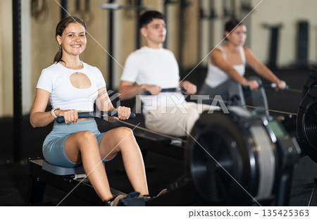 Young woman training her arms on machine 135425363