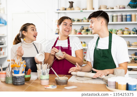 Two young women and young man making pottery Two young women and young man making pottery 135425375