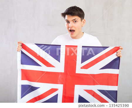 Surprised young guy holding UK flag 135425390