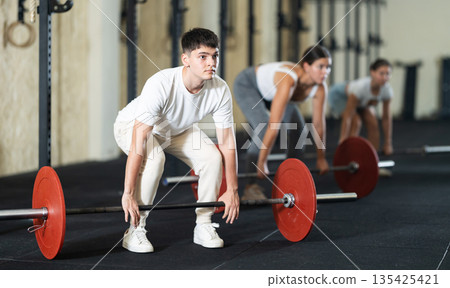 Young guy lifts barbell in gym 135425421