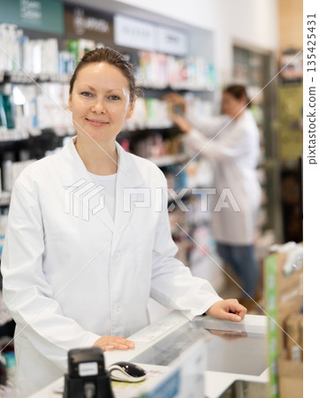 At pharmacy, friendly chemist is waiting for customers near cash register At pharmacy, friendly chemist is waiting for customers near cash register 135425431